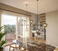 Modern living and dining area with a marble dining table, wooden chairs, a sofa, pendant lights, and a view of the outdoor deck.
