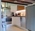 Modern kitchen with white cabinets, stainless steel appliances, and exposed wooden beams on the ceiling.