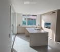 Modern kitchen with a central island, light-colored cabinets, and a large window overlooking a patio.