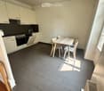 Modern kitchen with white cabinets, black countertops, and a dining area with a table and chairs.