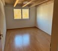Empty room, hardwood floor, wooden beams, white walls, single window, wall mounted power outlets