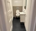 compact bathroom with toilet, sink, and mirror
