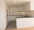 Modern kitchen with white cabinets, dark countertops, and a central island. Features include a sink with a modern faucet, built-in oven, and recessed ceiling lighting.