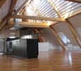 Modern kitchen with stainless steel appliances, wooden floors, and exposed wooden beams in the ceiling.