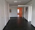 Empty hallway with white walls, dark flooring, and several doors leading to other rooms.