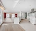 Modern, open-concept kitchen with white cabinets, stainless steel appliances, and light wood flooring.