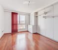 Empty room with wooden flooring, white walls, built-in white cabinets, and large windows offering a view of the outside.