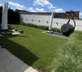 Well-maintained garden with neatly trimmed grass, decorative plants, covered patio furniture, and a small toy car on a paved area.
