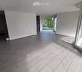 Empty room with grey tiled floor, white walls, large windows, and a staircase leading to another level.