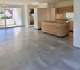 Open-plan kitchen and living area with tiled flooring, modern wooden island, built-in cabinets, and large sliding glass doors leading to a balcony.