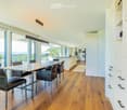 Bright dining area with a modern wooden dining table and chairs, large windows offering a scenic view, and built-in white cabinetry.