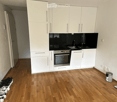 Modern kitchen with white cabinets, stainless steel oven, and wooden flooring.