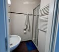 Modern bathroom with a bathtub, glass-enclosed shower, radiator, towel, and bath mat.