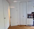 Modern kitchen with white cabinets, wooden floor, and a small coffee maker on the counter.