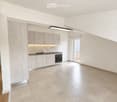 Modern kitchen with light-colored cabinets, a sink, stove, and oven. The space features tiled flooring and a sliding glass door leading to a balcony.