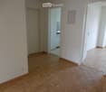 Empty hallway with wooden flooring, white walls, and doors leading to other rooms.