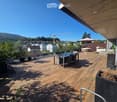 Wooden deck terrace with a dining set, umbrella, hot tub, and scenic mountain view.