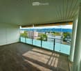 Balcony with tiled floor, glass railing, and a view of the city and mountains.