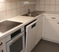 Modern kitchen with white cabinets, stainless steel sink, oven, and dishwasher.