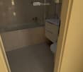 Modern bathroom with a bathtub, toilet, sink, and a glass-enclosed shower area. The space features tiled walls and floor, and a mirror above the sink.