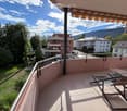 Balcony with a view of the surrounding area, including buildings and greenery, with a single chair placed on the floor.