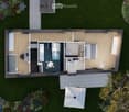 Top-down floor plan of a modern, compact house with a living area, bedroom, bathroom, and outdoor patio. Features include a staircase leading to a loft area, a small kitchen, and a covered outdoor seating area with a table and chairs.
