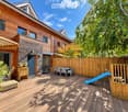 Wooden deck area with a table, chairs, a small slide, potted plants, and a wooden fence surrounding the space.