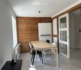 Modern dining area with a wooden table, white and black chairs, radiator, and a wooden accent wall.