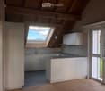 Modern kitchen with white cabinets, a central island, and a skylight window above the sink. The space features wooden flooring and ample natural light.