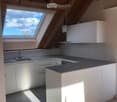 Modern kitchen with white cabinets, dark countertop, and skylight window above the sink.