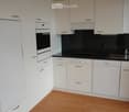 Modern kitchen with white cabinets, stainless steel appliances, and a black countertop.