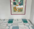 A bedroom with a colorful patchwork quilt on the bed and a framed mirror on the wall.