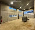 Warehouse: grey concrete walls, double doors, large windows, empty
