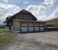 Modern two-story house with wooden exterior, large garage, and balcony on the upper level.
