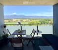 Balcony with a scenic mountain view, featuring a small wooden table, chairs, a sofa, and a round side table.