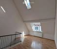 Empty attic room with wooden flooring, white walls, and skylight windows. No furniture or equipment present.
