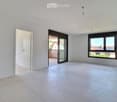 Empty room with white walls, tiled floor, large window, and sliding glass door leading to a balcony.