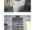 The image shows a utility room with a large white heat pump unit and an electrical panel with switches and labels.