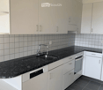 Modern kitchen with white cabinets, black granite countertop, stainless steel sink and faucet, built-in oven, and dishwasher.