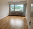 Empty room with wooden flooring, white walls, large windows, and a radiator. No furniture or equipment present.