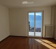 Empty room with wooden flooring, large sliding glass door leading to a balcony with a scenic mountain view.