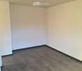 Empty room with beige walls and dark tiled floor, no furniture or equipment visible.