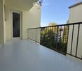 Balcony with white flooring, black metal railing, and a door leading to an interior space.