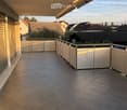 Balcony with tiled floor, metal railing, and a retractable awning, overlooking a residential area with houses and trees.