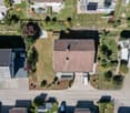 Aerial view of a residential area with multiple houses, gardens, driveways, and parked cars.