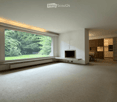 Bright living room with large windows, fireplace, dining area visible through an open doorway.