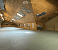 An empty room with wooden walls and ceiling, posters on the walls, and a concrete floor.