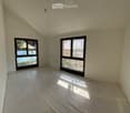 Unfurnished Room. Empty room with light-colored walls and a concrete floor, featuring two large windows that offer a view of a pool and outdoor area.