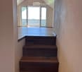 Wooden staircase leading to an open loft area with exposed wooden beams and a skylight window above.