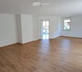 Empty room with wooden flooring, white walls, and large windows. No furniture or equipment present.